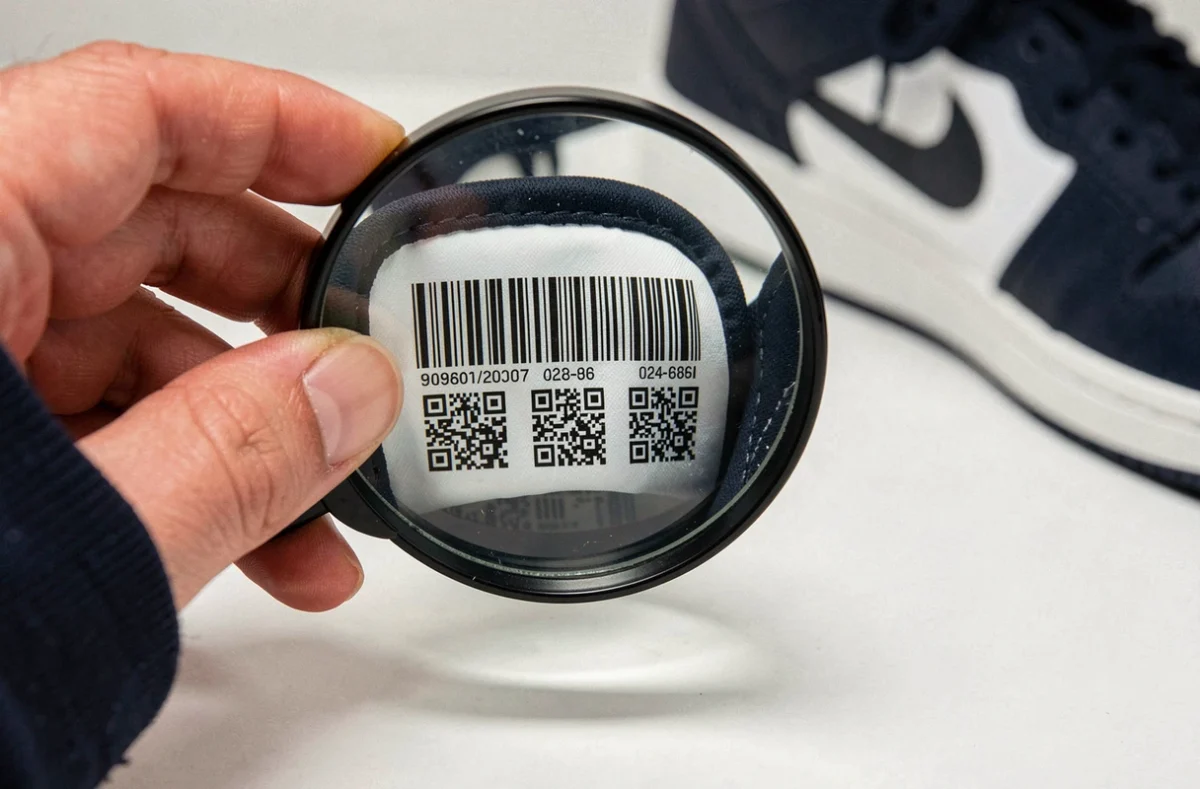 Gros plan sur l'étiquette UPC d'une basket Nike inspectée à la loupe pour détecter la contrefaçon